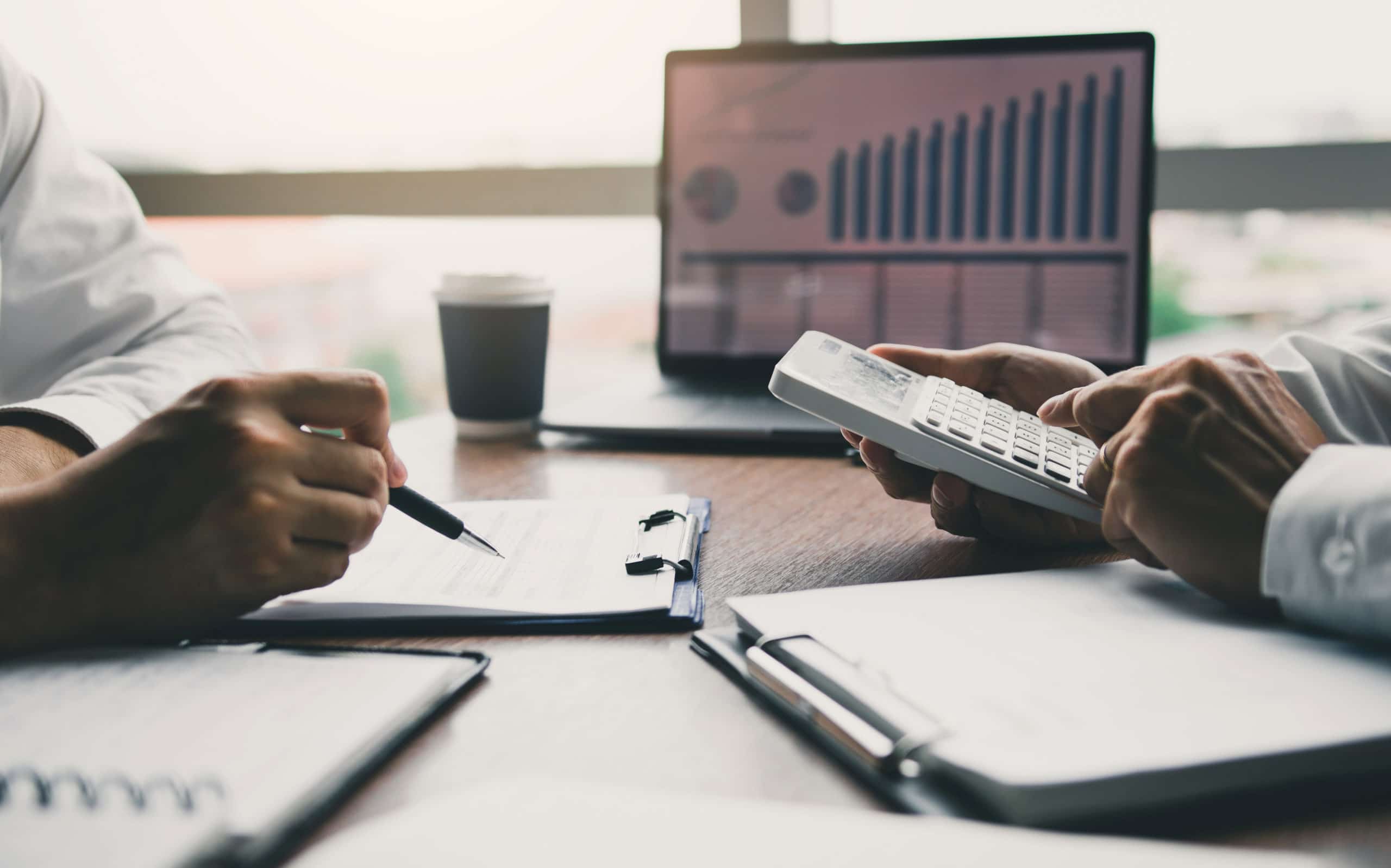 Two business people talking about report graph and analysis about finance budget or cost company and using calculator in office room.